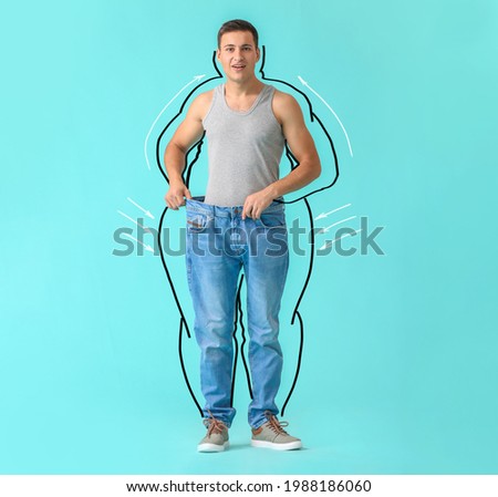 Surprised young man after weight loss on color background Royalty-Free Stock Photo #1988186060