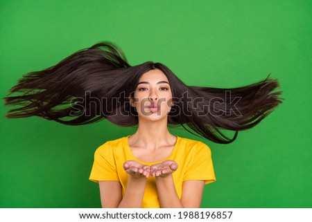 Photo of attractive charming young woman send air kiss you hand fly hair isolated on green color background