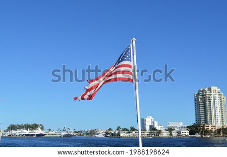 American Flag flying in the background of Fort Lauderdale Canals and city skyline on a sunny summer day.