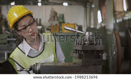 Asian professional mechanical engineer or operation woman wearing uniform goggles safety working on workshop metal lathe industrial manufacturing factory, Heavy industry lathe worker woman