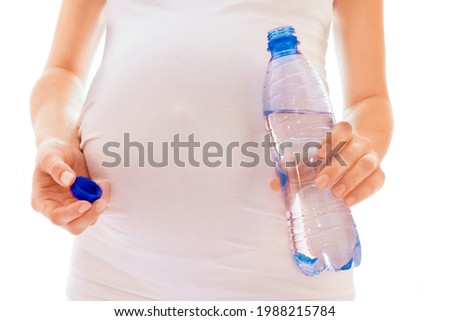 beautiful young pregnant girl on a white background with a bottle