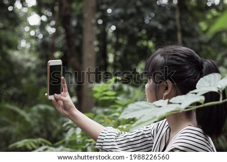 Selfie photo concept: Asian Adolescents or Start up Adolescents using smartphone for selfies at forest park, beautiful scenery for peaceful in spring tranquility and refreshing of rain forest Thailand