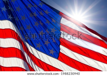 Sunburst behind America flag in blue sky