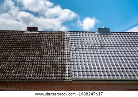 A half cleaned house roof shows the before and after effect of a roof cleaning. Royalty-Free Stock Photo #1988247617