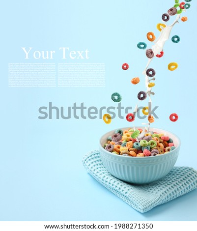 Pouring of tasty cereal rings and milk into bowl on color background with space for text Royalty-Free Stock Photo #1988271350