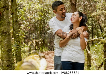 Hispanic couple in love hugging in the park - man hugging his wife in the middle of nature - Latin couple Royalty-Free Stock Photo #1988283821