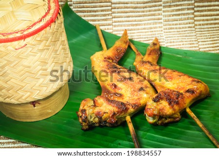 grilled chicken and sticky rice box are on  banana leaf.