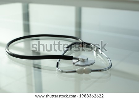 Black stethoscope lies on a glass table