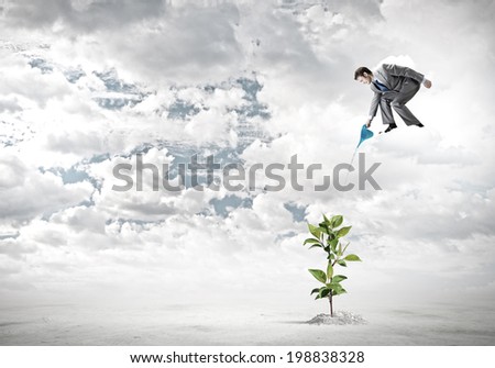 Young businessman standing on cloud and watering sprout