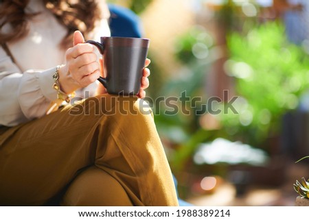 Green Home. Closeup on middle aged woman with long wavy hair with cup of hot chocolate at home in sunny day.