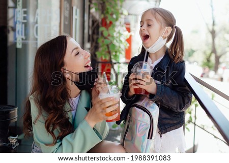Stock Photo - Mom and little daughter with takeaway drinks in a cafe. Opening a cafe. Work cafe with security measures for Covid-19. Work during covid-19 or coronavirus