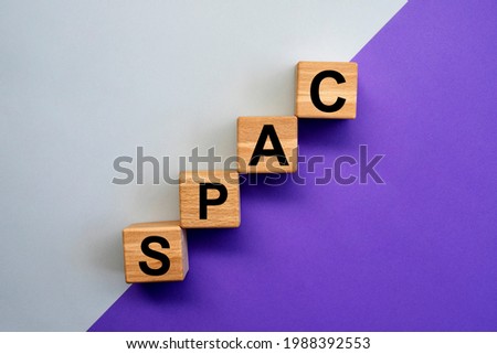 SPAC, special purpose acquisition company symbol. Wooden cubes with word 'SPAC' on beautiful gray and purple background, copy space. Business and SPAC, special purpose acquisition company concept.