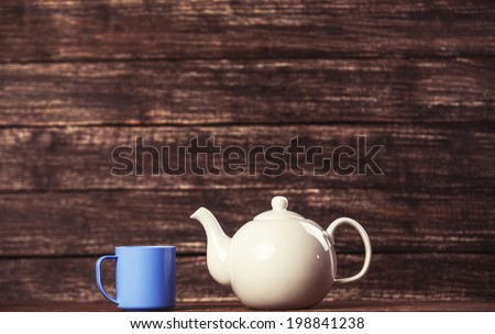 Teapot and cup of tea on wooden table.