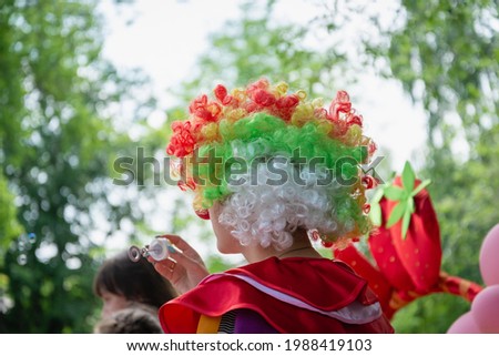 Clown with colored hair on the background of the forest.