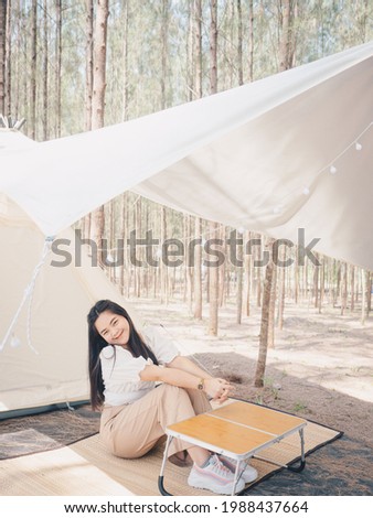 Happy Asian teenage girl in front of camp tent. Outdoor activity. Adventure travel and holiday vacation concept.