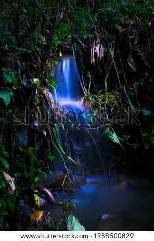 long exposure picture of little waterfall with glowing blue water.