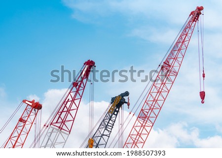 Crawler crane against blue sky and white clouds. Real estate industry. Red crawler crane use reel lift up equipment in construction site. Crane for rent. Crane dealership for construction business. Royalty-Free Stock Photo #1988507393
