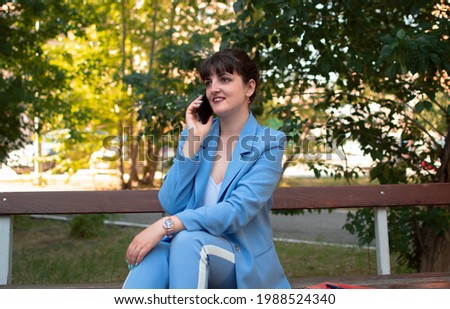 Portrait of a stylish smiling business woman in fashionable clothes, calling on a mobile phone near the office. women's business style.