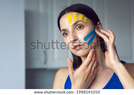 portrait of a young woman with pasted konesiotape for rejuvenation and face tightening without surgery