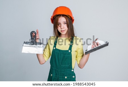 teen girl laborer in protective helmet and uniform use spatula tool, equipment
