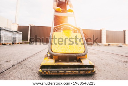 The worker tamping a gravel by the vibration plate Royalty-Free Stock Photo #1988548223