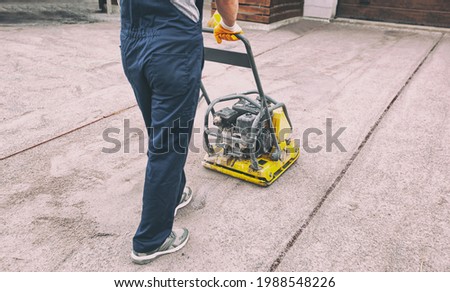 The worker tamping a gravel by the vibration plate Royalty-Free Stock Photo #1988548226