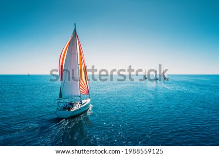 Regatta sailing ship yachts with white sails at opened sea. Aerial view of sailboat in windy condition. Royalty-Free Stock Photo #1988559125