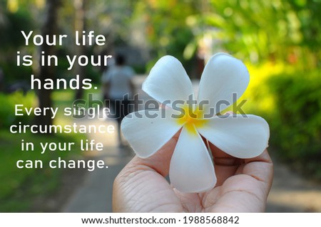 Your life is in your hands. Every single circumstance in your life can change. Inspirational motivational words with white Bali frangipani flower in the hand on spring or summer backgrounds. Royalty-Free Stock Photo #1988568842