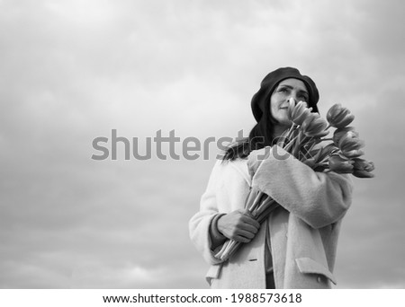 Woman with Spring Flower bouquet. Happy surprised model woman smelling flowers. Mother's Day. Springtime