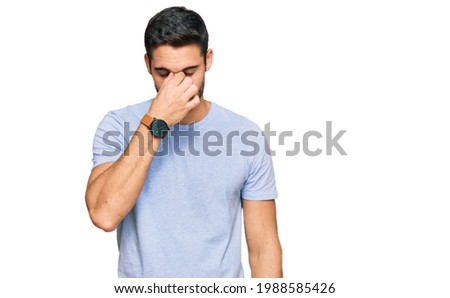 Young hispanic man wearing casual clothes tired rubbing nose and eyes feeling fatigue and headache. stress and frustration concept. 