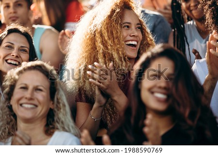 Woman watching a sport event and clapping. Excited sports fan applauding and celebrating her team's victory. Royalty-Free Stock Photo #1988590769