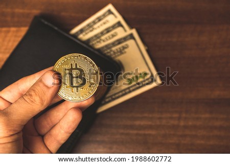 Man hold bitcoin coin and leather wallet with dollar on the background, new money concept photo