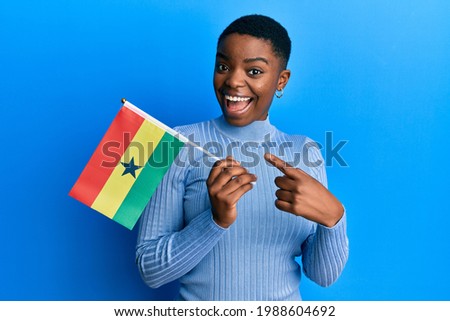 Young african american woman holding ghana flag smiling happy pointing with hand and finger 