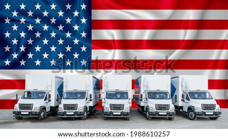 US flag in the background. Five new white trucks are parked in the parking lot. Truck, transport, freight transport. Freight and logistics concept