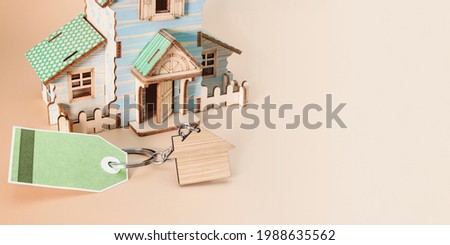 The concept of mortgage, sale and rental of housing and real estate. Buying a home. A mock-up of house on a delicate beige background. Tag with place for text. Banner format. Copy space