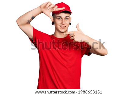 Young caucasian boy with ears dilation wearing delivery uniform and cap smiling making frame with hands and fingers with happy face. creativity and photography concept. 