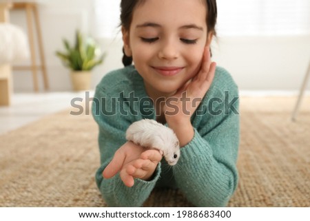 Little girl with cute hamster at home