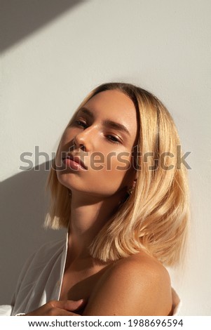 portrait photo of a gentle woman in a white shirt. Photo of a blonde in the sun. A girl with bright makeup, a lot of sparkles on her face. fashion photography
