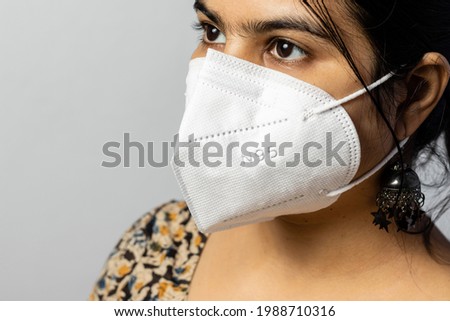 Close up head shot of an Indian woman wearing N 95 mask on white background Royalty-Free Stock Photo #1988710316