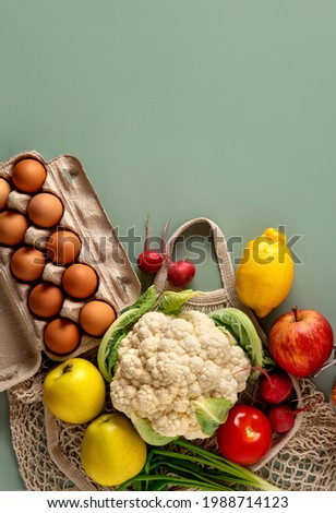 Zero waste shopping concept on green background. Fresh vegetables and fruits in eco cotton bags on table. Zero waste concept with copy space