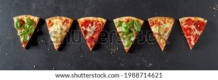 Line of Italian pizza portions with a variety of trimmings displayed in a panorama banner or header on slate for menu advertising Royalty-Free Stock Photo #1988714621