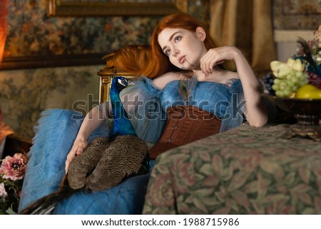 Art photo of a red-haired girl with a peacock in a retro room