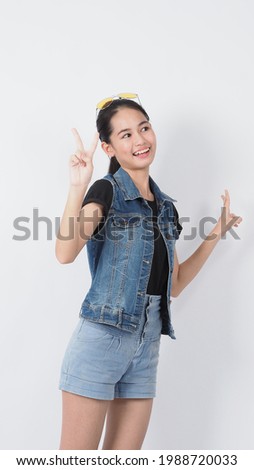 Asian Young woman gesture posing on white background. represent cheerful and confident. Showing gestures such as mini heart Okay Thumb up or point out. Happy amazed excited and surprised Jacket jeans.