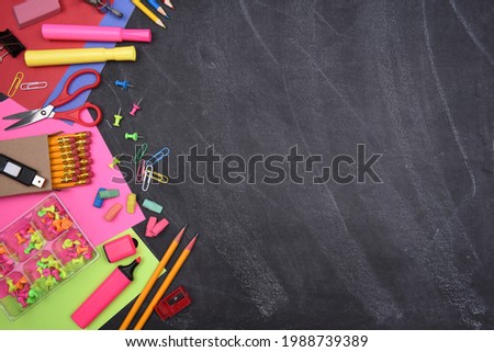 School Supplies: Still life on erased Chalkboard of assorted school supplies with copy space.