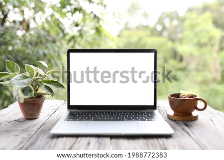Laptop white mock up blank screen and plant pot and tea cup on table outdoor