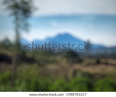 Defocused abstract background of the landscaped silhouette of Mount Ijen in Indonesia covered in fog with blue sky.