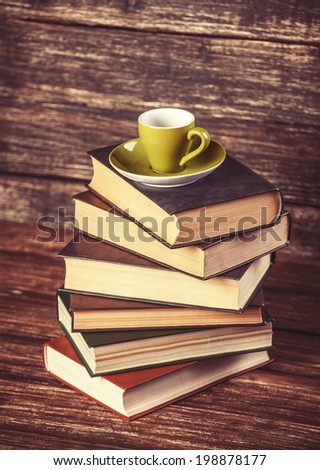 Books and cup of coffee on wooden background.