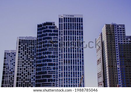 Housing for urban families in a residential area. Geometric facades of houses against the blue sky. Infrastructure of the sleeping district of the city