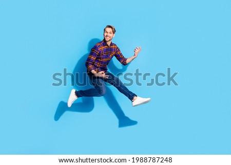 Full body photo of happy cheerful funny young man play imagine guitar jump up air isolated on blue color background