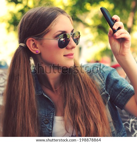 Hipster girl uses a smartphone. Photo toned style instagram filters